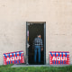 A voter walks into a polling place with signs that read "Vote Aqui Here"