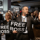 Libertarian Party delegates wait to enter a ballroom for a speech by former President Donald Trump holding signs that say "Free Ross"