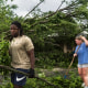 Will Worthey, left, and Lindsey Worthey of Rogers, help clear debris from a downed tree in Rogers, Ark., on Sunday, May 26, 2024.