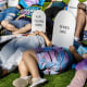 Protesters lie on the ground holding cardboard signs shaped like tombstones that read "Depression," "R.I.P. Trans Youth," "Denied Care" and "Overdosed"