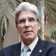 Julio Frenk poses for a portrait in front of a palm tree