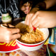 Tourists mix a bowl of instant noodles.