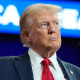 Donald Trump stands at a podium and extends his arms