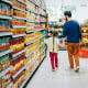 Father and daughter shopping at grocery store, they are holding hands while walking down the snack aisle.