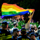 A participant holds a rainbow flag next to police officers