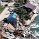 An aerial view of damaged housing near a river