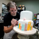 Jack Phillips decorates a white fondant cake in his shop