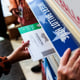 A hand places a ballot into a ballot box