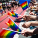 A row of hands holding rainbow flags outside during a parade