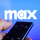 Max logo displayed on a tv screen and a tv remote control being held by a hand