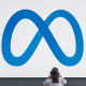 A visitor takes photographs of Meta Platforms signage outside the company's headquarters in Menlo Park