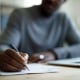 Man writing in front of laptop