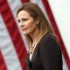 Amy Coney Barrett stands in front of an American flag