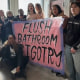 People hold a sign saying "Flush Bathroom Bigotry"