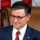 Mike Johnson holds a gavel at a podium, American flag hangs behind him