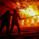 Firefighters spray water on a burning home.