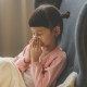 Asian small girl blowing her nose into a napkin