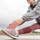 Fit Mature Woman Stretching Muscles Folding Torso over Leg in Park