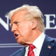 Mike Johnson, left, and Donald Trump speak to each other on stage