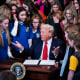 President Donald Trump is surrounded by girl athletes as he signs an executive order banning transgender athletes from participating in women's sports.