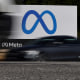 Cars drive past a sign of Meta