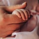 A close-up of a mother gently holding her baby's tiny hand,.