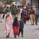 Kashmiri villagers are escorted by police as they walk after.