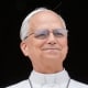 Pope Leo stands and smiles with his hands clasped