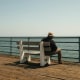 A man sat alone on a bench looking out at the sea