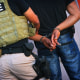 A handcuffed man taken away by a police officier.