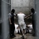 Prisoner led by two security officers inside a cell.