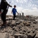 A security guard asks a child to stop walking over the rubble of a building destroyed by U.S. strikes on April 27, 2025 in Sana'a, Yemen. 