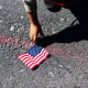 A boy reaches over to pick up a U.S. flag