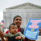 Olga Urbina holds a sign that reads "American Born Children are American Children" as her son Aers holds an American flag.
