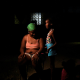 Yesica Pozo sits in the dark outside her apartment with her children 