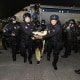 An alleged gang member escorted from a plane by El Salvador police