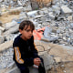 A Palestinian boy sits on rubble