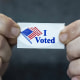 Two hands hold an "I Voted" sticker