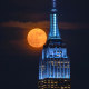 The full moon rises behind the Empire State Building in New York on June 10, 2025.