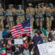 Demonstrators holding signs and flags face California National Guard members standing guard outside the Federal Building 