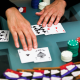 Niman Kenkre plays poker, his hands are seen on a table with playing cards and poker chips