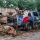 A destroyed SUV draped in a Texas State flag sits next to the road after flash flooding