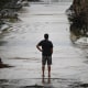 A man looks at a damaged road after severe flash flooding