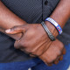 Two arms crossed over one another, a bracelet with the text "Haiti" on it is worn on his wrist