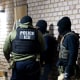 ICE agents outside a residential door.