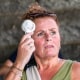 A woman uses a handheld electric fan outside