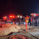 An emergency crew stands outside on a road at night near emergency vehicles