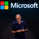 Satya Nadella speaks under Microsoft signage.