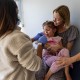 Dr. Neville Anderson, right, tries to cheer up and distract a young patient receiving her DTap Polio and MMR Chickenpox vaccinations in Los Angeles on March 25, 2025.