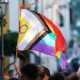 An LGBTQIA flag is waved above a crowd